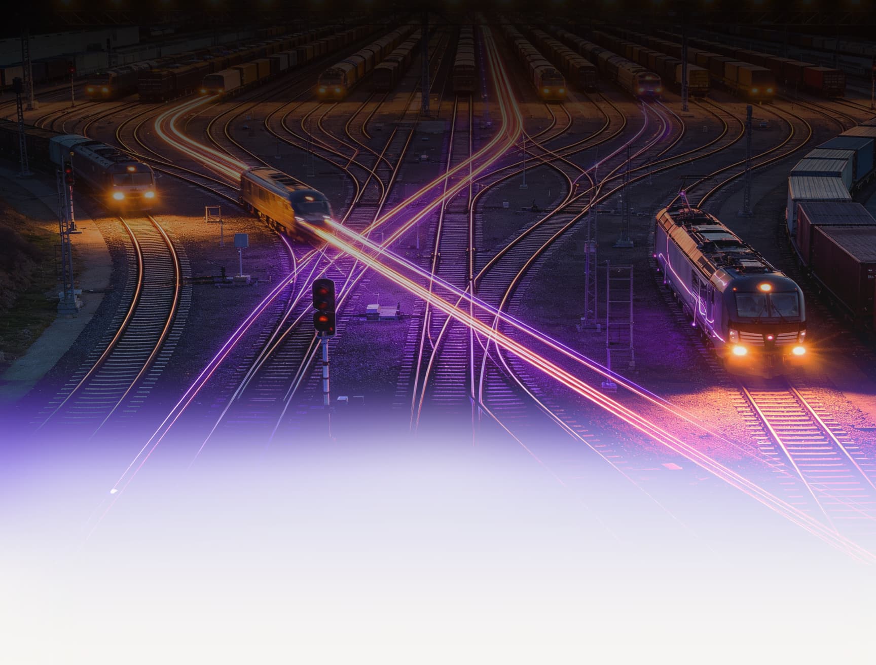 Ein Bahnbetriebswerk bei Nacht mit Zügen und Lichtspuren vorbeifahrender Züge